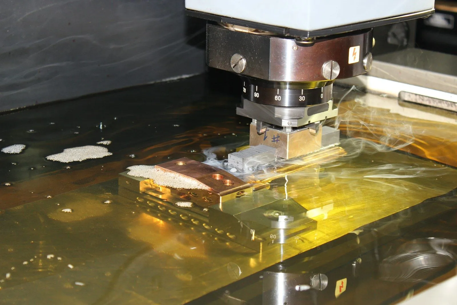 Electrodo de cobre erosionando una pieza sumergida en aceite dieléctrico